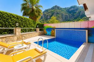 a swimming pool with yellow lounge chairs and a swimming pool at Villa Aysel Paradise in Dalyan