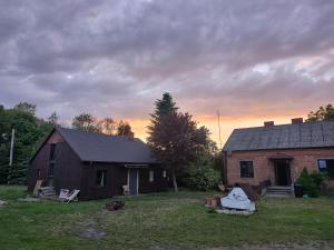 a barn and a house with a sunset in the background at Weekendowo Miejsce i Czas Agroturystyka in Wyszogród
