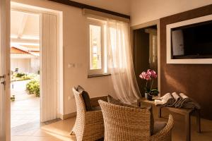 a living room with wicker chairs and a television at Capo Vaticano Suites in Capo Vaticano