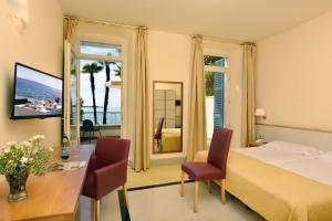 ガルドーネ・リヴィエラにあるHotel Monte Baldo e Villa Acquaroneのベッド、テーブル、椅子が備わるホテルルームです。