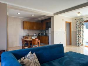 a living room with a blue couch and a kitchen at Baia da Barca in Madalena