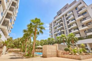 an apartment complex with palm trees and a swimming pool at Stunning Studio Pool View CFC Casablanca in Casablanca