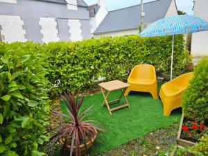 a patio with two chairs and a table and an umbrella at penty vero in Plobannalec-Lesconil