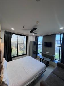 a bedroom with a large white bed and windows at Hotel 7 Square in Surat