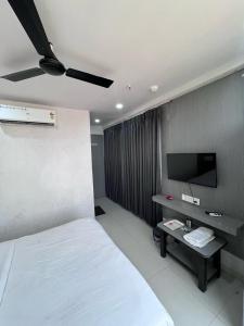 a bedroom with a white bed and a tv at Hotel 7 Square in Surat