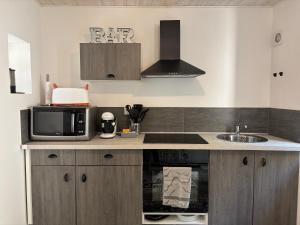 a kitchen with a microwave and a sink at Escapade en Auvergne - centre historique - 3 personnes in Olliergues +14 photos