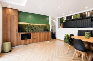 a dining room with a table and a kitchen with green cabinets at Palheiro 81 Ocean View in Costa Nova