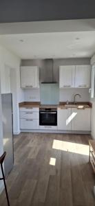 an empty kitchen with white cabinets and a sink at Appartement Neuf avec Balcon in Hendaye