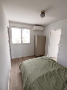 a white bedroom with a bed and two windows at Appartement Neuf avec Balcon in Hendaye