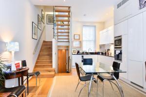 a kitchen and dining room with a glass table and chairs at Elegant 3 bed apt with rooftop terrace in Pimlico in London