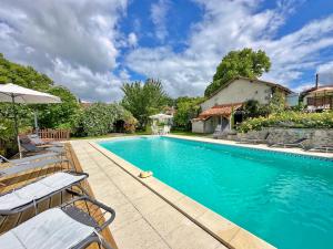 a swimming pool with chairs and a house at La Colline de Tilleul - Les Deux Puits - Cosy Cottage with swimming pool near Aubeterre in Saint-Romain
