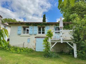 a house with blue shutters and a umbrella at La Colline de Tilleul - Les Deux Puits - Cosy Cottage with swimming pool near Aubeterre in Saint-Romain