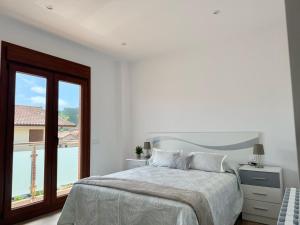 a white bedroom with a large bed and a window at La Villa de Miera - 12809 in Ajo