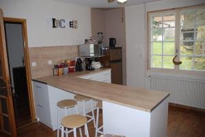 a kitchen with a counter top and two stools at Etape motards chez Fred et Flo in Compreignac
