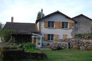 a white house with brown windows and a yard at Etape motards chez Fred et Flo in Compreignac