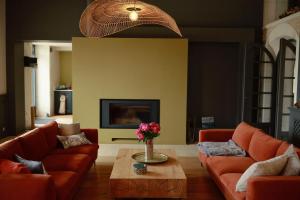 a living room with orange couches and a coffee table at Maison d'Hôtes Le Clos de Bacchus in Julienne