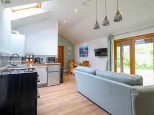 a living room with a blue couch and a kitchen at Henlle Home Farm in Oswestry