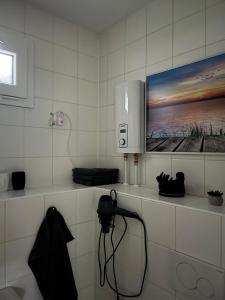 a bathroom with a tv on a white tiled wall at Tiny house am Wald eingezäunt in Meißendorf +17 photos