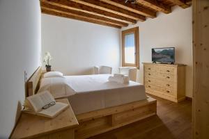 ein Schlafzimmer mit einem großen weißen Bett und einer Kommode in der Unterkunft Rum Oliero in Valbrenta 