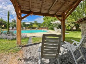 a pair of chairs sitting under a pergola next to a pool at Entire apartment with swimming pool near Aubeterre in Saint-Romain