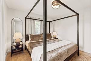 a bedroom with a canopy bed with white walls at The Luxury Haus in Grove City