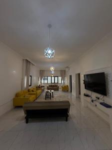 a large living room with yellow couches and a flat screen tv at Al Rabi Rest House in Khor Fakkan