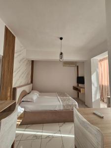 a bedroom with a bed and a table and a television at Hotel Rozafa Velipoje in Baks-Rrjoll