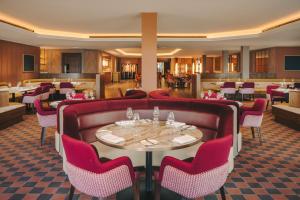 a restaurant with a red couch and tables and chairs at Fairmont Cheshire The Mere in Knutsford