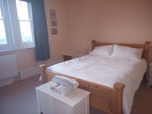 a bedroom with a large bed with white sheets at Castle Road in Castletown