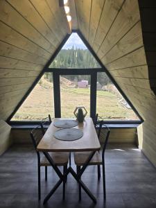 a table and chairs in a room with a large window at Synevyr House 2 in Synevyrsʼka Polyana