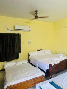 two beds in a room with yellow walls at The ARCS in Madurai