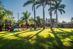 a park with palm trees and a playground with swings at El Rosedal Cataratas in Puerto Iguazú