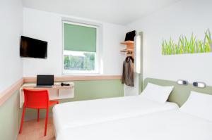 - une chambre avec un lit et un bureau avec un ordinateur portable dans l'établissement ibis Budget Clermont Ferrand Centre Montferrand, à Clermont-Ferrand
