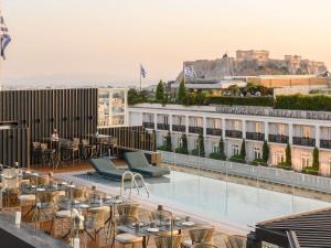 a rooftop patio with tables and chairs on a building at Athens Capital Suites-MGallery Collection in Athens