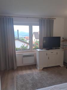 a living room with a television and a large window at Pod jedľou in Liptovský Trnovec