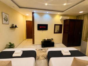 a hotel room with two beds and a tv at Oyal Scarab Pyramids View in Cairo