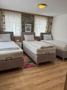 three beds in a room with wooden floors and windows at Elgi Apart in Serfaus
