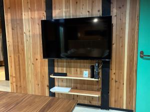 a flat screen tv on a wooden wall at 赤瓦のお宿みあげむい in Kunigami