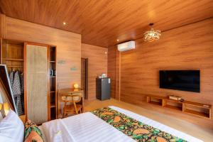 a bedroom with a bed and a flat screen tv at Uma Nandhi Villa Ubud in Tegalalang