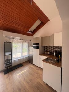 a kitchen with white cabinets and a wooden ceiling at Tisza-tó Porta in Tiszafüred