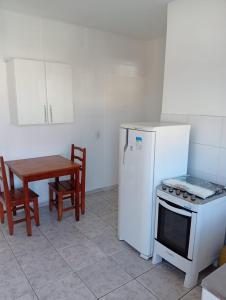 a kitchen with a stove and a table and a refrigerator at Apartamento 45A in Paulínia