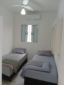 two beds in a room with a ceiling fan at Apartamento 45A in Paulínia