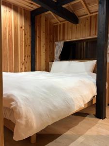a bed in a room with wooden walls at 赤瓦のお宿みあげむい in Kunigami