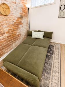a green couch in a room with a brick wall at Downtown Detroit Hidden Gem Walk to Venues & DMC in Detroit