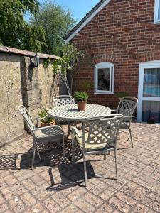 a table and chairs on a brick patio at Brook Lodge, One bed house in AONB Dorset with swimming pool in Iwerne Minster