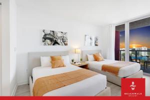 two beds in a room with a window at Upper-Floor Studio Balcony Sleeps 4 in Hallandale Beach