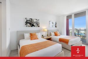two beds in a room with a window at Upper-Floor Studio Balcony Sleeps 4 in Hallandale Beach