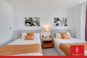 two beds in a room with two pictures on the wall at Upper-Floor Studio Balcony Sleeps 4 in Hallandale Beach