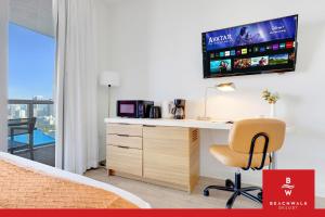 a bedroom with a desk with a television on a wall at Upper-Floor Studio Balcony Sleeps 4 in Hallandale Beach +37 photos
