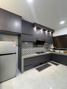 a kitchen with black cabinets and a white refrigerator at Seroja Homestay Gopeng in Gopeng